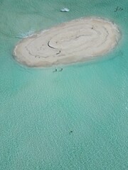 This image captures a breathtaking aerial view of a small, circular sandbank in the Maldives. 