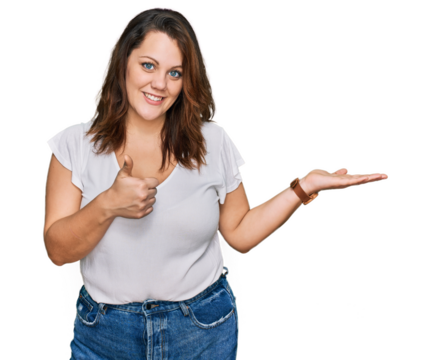 Young plus size woman wearing casual white t shirt showing palm hand and doing ok gesture with thumbs up, smiling happy and cheerful