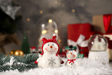 Funny snowmen figures and fir branch on artificial snow, closeup