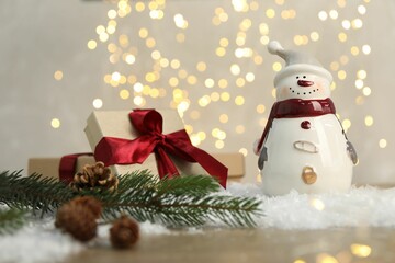 Funny snowman figure and other decor on table against blurred lights