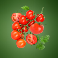 Fresh tomatoes with leaves in air on green background