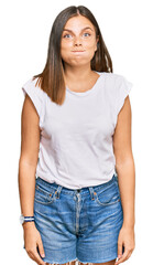 Obraz premium Young caucasian woman wearing casual white tshirt puffing cheeks with funny face. mouth inflated with air, crazy expression.