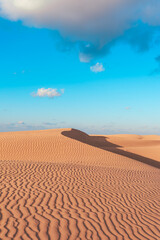 Naklejka premium wave texture on orange desert with blue sky at background