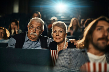 Happy senior couple enjoying movie at the cinema