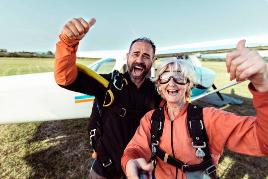 Happy senior woman celebrating successful skydive with instructor