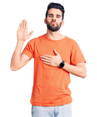 Young handsome man with beard wearing casual t-shirt swearing with hand on chest and open palm,...