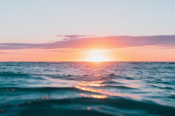 Obraz premium Ocean sunset. Peaceful scene of a sun setting over the ocean, with the horizon obscured by the waves.