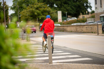 Cyclist in red jacket riding through urban pedestrian crossing