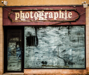 Abandoned photography shop facade with weathered sign and grungy windows
