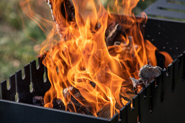 Grill with burning wood and a bright fire close-up