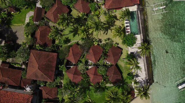 Aerial Drone Footage of Tropical Beachside Resort with Pool and Palm Trees.