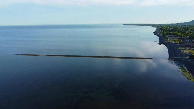 Les vestiges d'un ancien quai traverse une immense baie &agrave; l'eau calme r&eacute;fletant le bleu du ciel sur le littoral  d'un village c&ocirc;tier aux habitations parsem&eacute;es. ( Maria, Gasp&eacute;sie, Baie-des-Chaleurs )