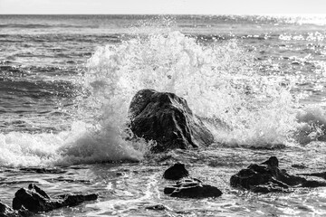 Black lava rocks in the surf at the “Pointe aux Piments” in the west of the tropical vacation...