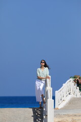 Fototapeta premium beautiful brunette woman walking on the bridge by the sea