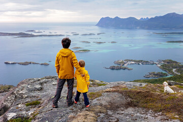 Family with children and pet, hiking Sukkertoppen trail on Senja island, Norway