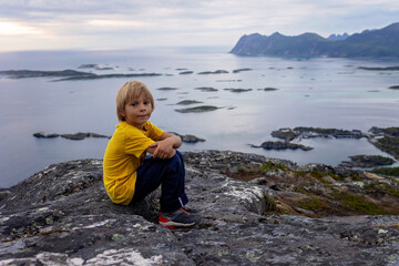 Family with children and pet, hiking Sukkertoppen trail on Senja island, Norway