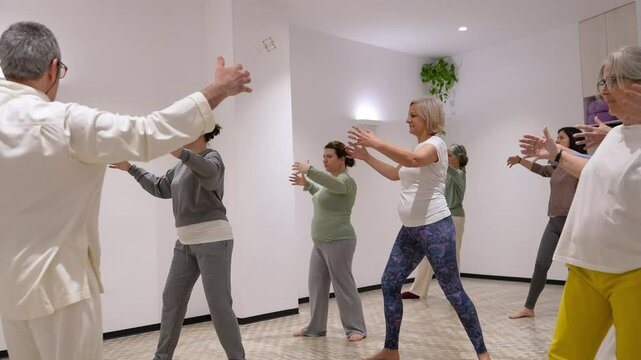 A group of people are practicing Tai Chi in a room
