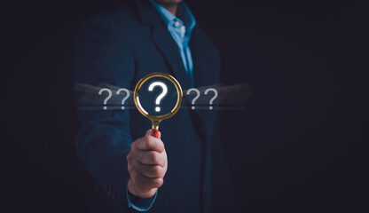 Question mark and problem analysis concept.Businessman hand holding magnifying glass with question...