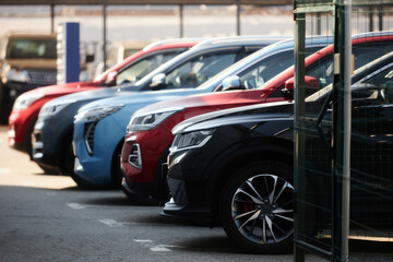 Side view of demo cars of various models and colors displayed in parking lot of modern dealership...