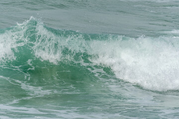 Wave of the green and blue Atlantic Ocean at the edge of a beach in the Iroise Sea.