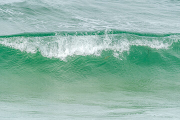 Wave of the green and blue Atlantic Ocean at the edge of a beach in the Iroise Sea.