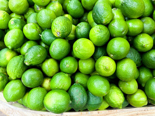 Fresh limes piled together in a market basket, showcasing vibrant colors and textures