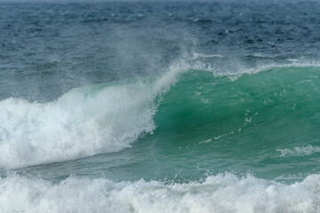 Wave of the green and blue Atlantic Ocean at the edge of a beach in the Iroise Sea.