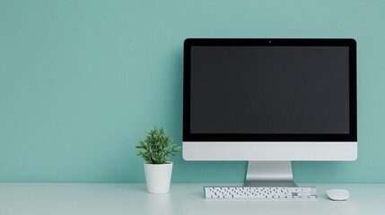 Minimalist desk setup with a sleek computer, white keyboard, and a small plant, promoting a fresh and clean work environment