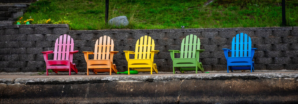 Colorful Adirondack chairs on a concreate dock in summer