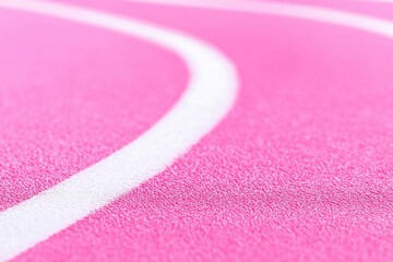 Close-up of a pink running track with white lines, on a pink background
