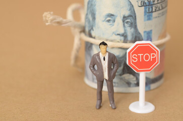 the businessman with money banknotes stands beside a stop sign, illustrating a critical moment of financial restraint.