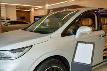 Silver display model of new SUV car demonstrated in vehicle showroom next to information stand with...