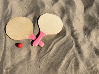The rackets and the ball of a beach tennis set lies in the sand on the beach