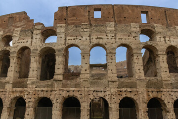 Roman Colosseum, the largest ancient amphitheatre ever built, Italy. Arches, exterior facade. ...