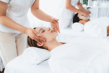 Obraz premium Serene modern daylight ambiance of spa salon, couple customer indulges in rejuvenating with facial skincare mask. Facial skin treatment and beauty cosmetology procedure for face. Quiescent