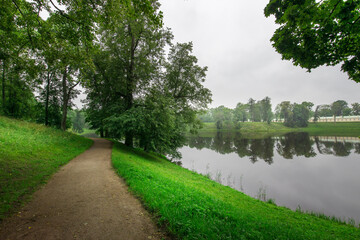 A path runs along the edge of a lake, with trees lining the sides