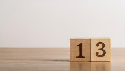 Wooden cube with number 13 on wooden table, white wall on background. Event planner, calendar