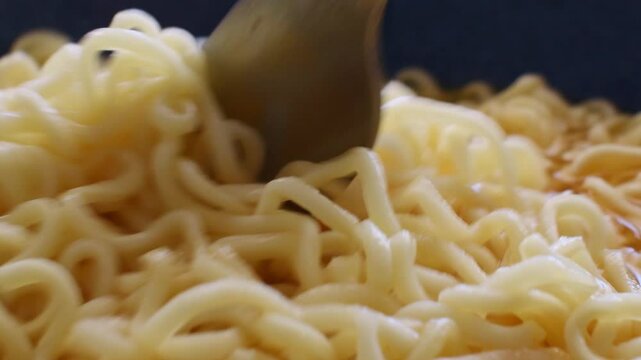 Instant noodle soup close up with a fork. Stirring noodles. Simple and speed food. 
