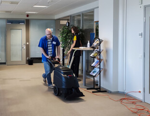 A Caucasian man washes carpet from stains using a Carpet washing machine.
