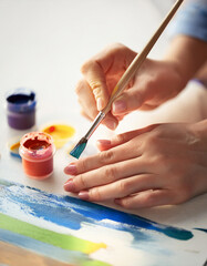 Educational pastime develops creative abilities in child concept. mother of her little daughter in a sunny cozy living room, mom teaches the little girl how to use paint and colored pencils
