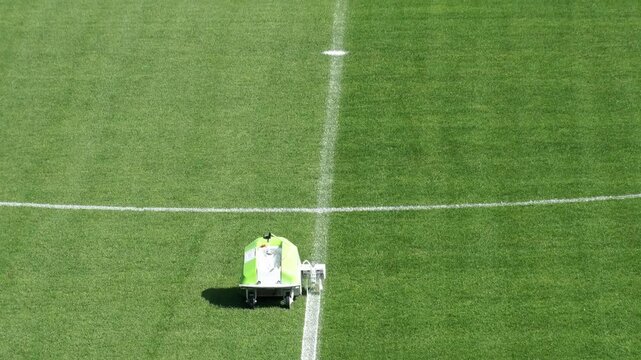 Line marking machine drawing white line on football field