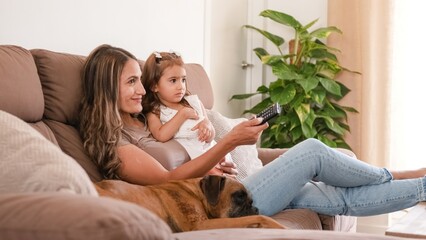 Happy family with cute dog watching TV on couch at home