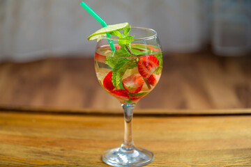 Glass with fruit cocktail strawberry mint lime with ice on wooden table