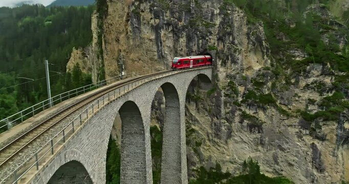 Railway scenic route in Switzerland. Express red swiss train in Swiss Alps. Landwasser Viaduct world heritage sight with luxury Glacier and Bernina express summer scenery
