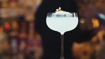 Closeup hand bartender using strainer in vodka coconut smooth fizzy cocktail at luxurious counter...