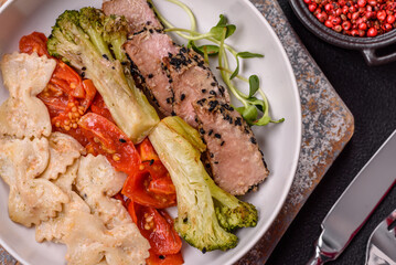 Bowl with slices of baked tuna with broccoli, tomatoes and fusili pasta