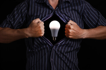 Man tears off his shirt, exposing glowing light bulb inside, symbolizing ideas and creativity.