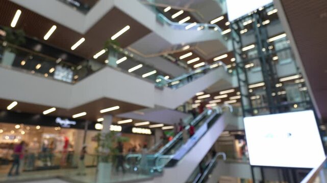 Blurred scenes capture shoppers and commuters riding escalators in multilevel shopping center, showcasing hustle and bustle of vibrant retail environment