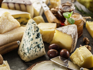Variety of different cheese chunks on wooden table close up..