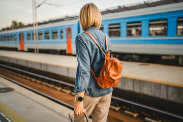 back view of mature woman use cellphone and walk with suit case